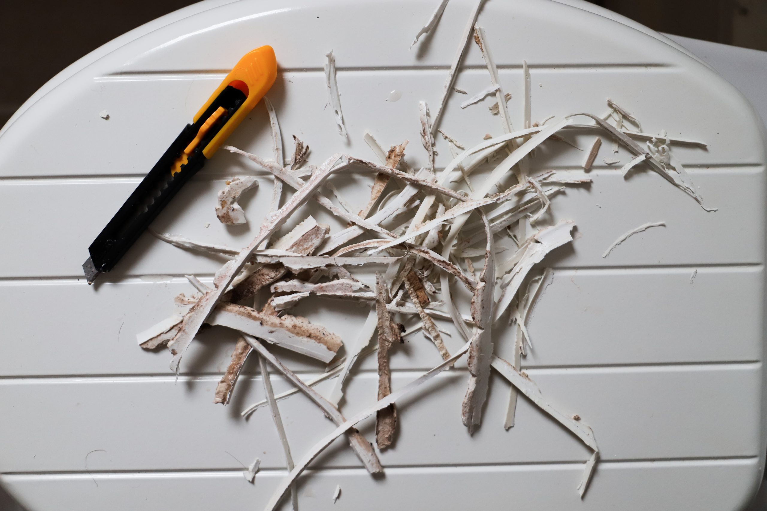 Removing old sealant from a bathtub, image of old sealant and blade.