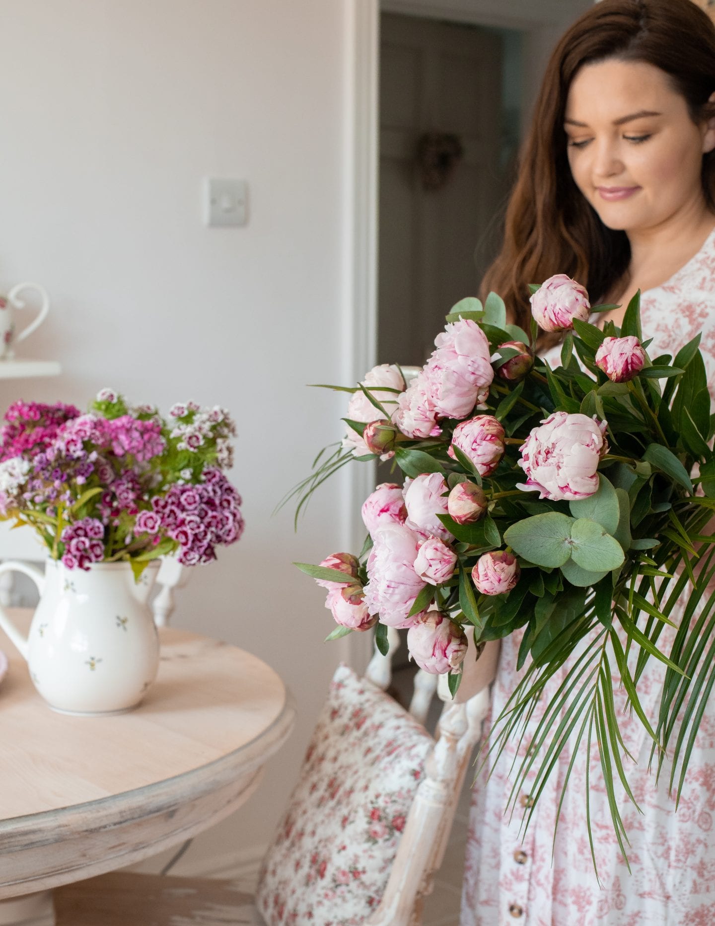 Girl with peonies in floral dress. 