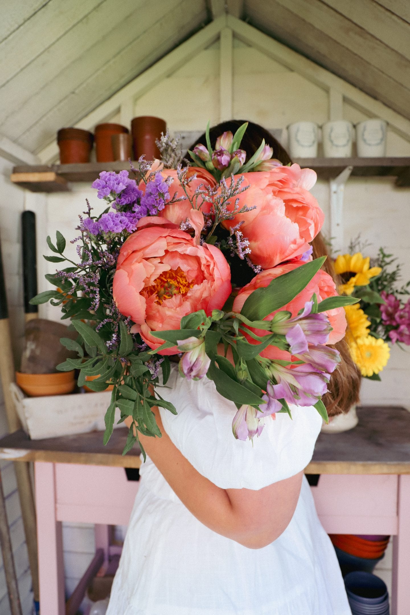 Tiny She shed makeover. Girl standing with peony flowers.