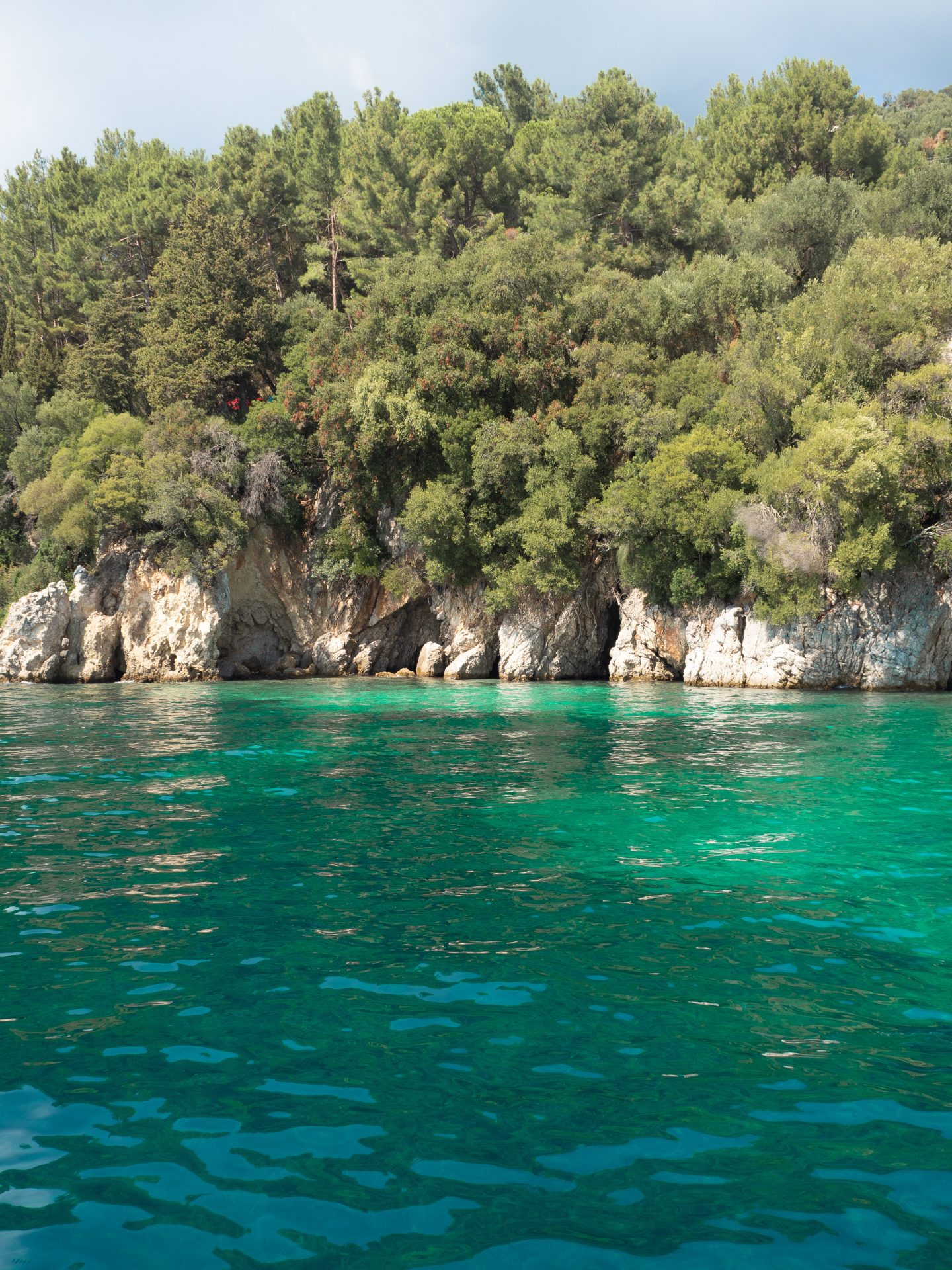 Boat trip Corfu. Turquoise blue waters by a cave. 