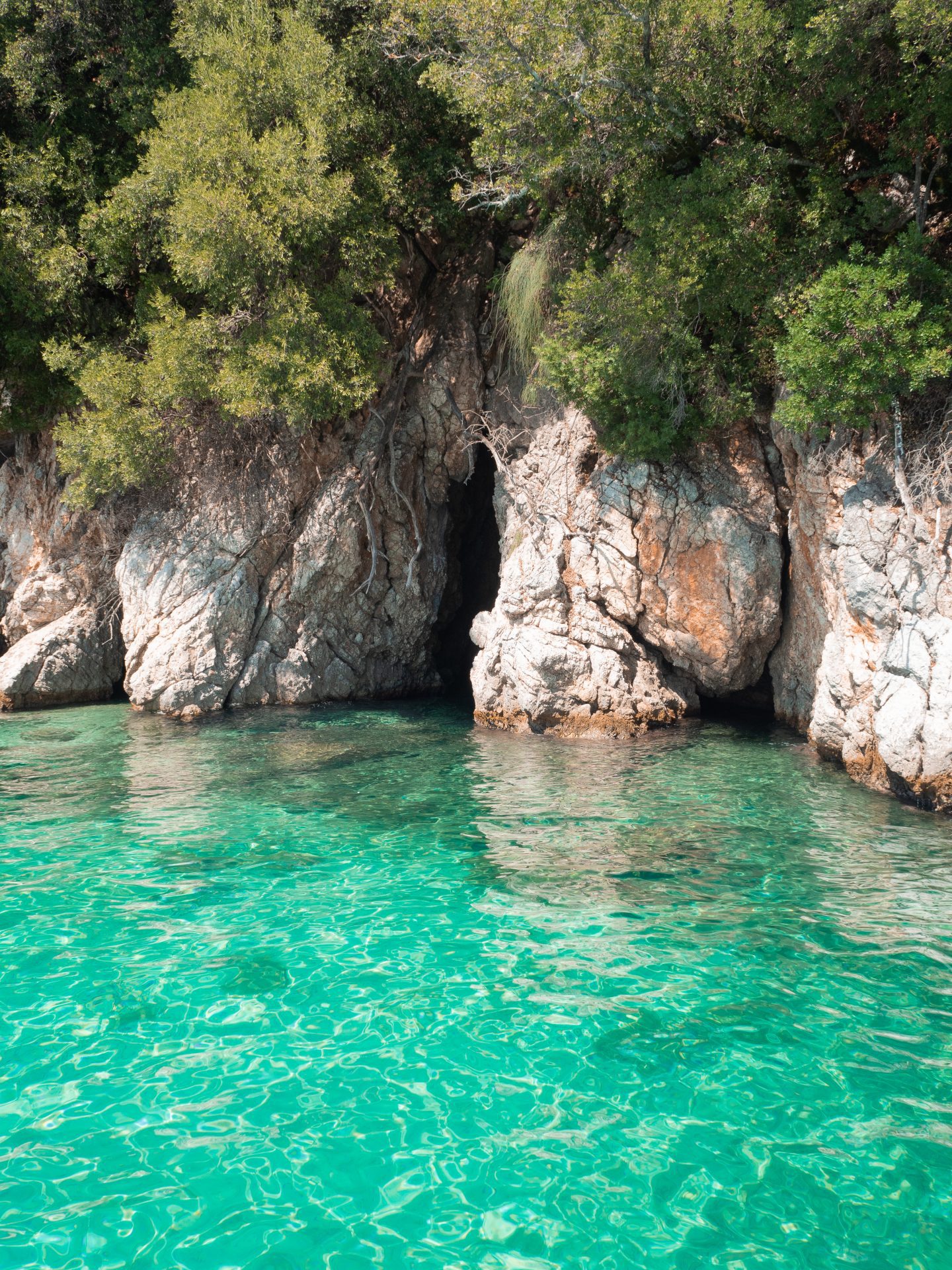 Boat trip Corfu. Turquoise blue waters by a cave. 